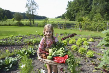 Mädchen im Garten hält Gemüse